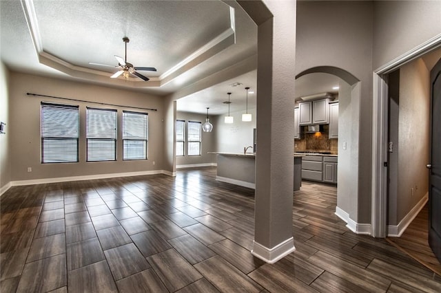 8022 Calgary Dr, Corpus Christi, TX 78414 - unfurnished living room featuring a ceiling fan, arched walkways, a tray ceiling, wood finish floors, and a textured ceiling