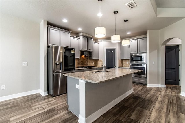 8022 Calgary Dr, Corpus Christi, TX 78414 - kitchen with stainless steel appliances, arched walkways, gray cabinets, backsplash, and recessed lighting