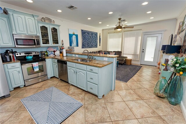 kitchen with kitchen peninsula, sink, ornamental molding, ceiling fan, and appliances with stainless steel finishes