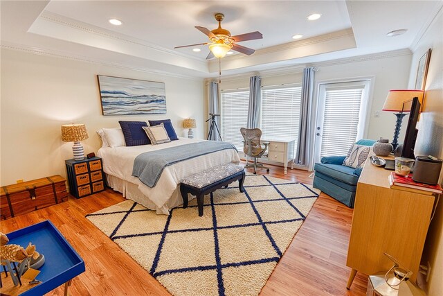 bedroom featuring ceiling fan, wood-type flooring, crown molding, and a tray ceiling