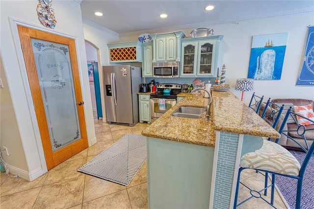 kitchen with stainless steel appliances, sink, kitchen peninsula, ornamental molding, and a kitchen breakfast bar