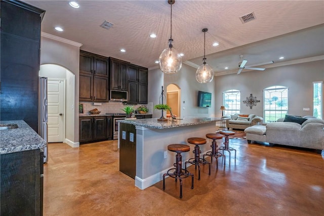 4609 Tuscan Way, Corpus Christi, TX 78410 - kitchen with finished concrete flooring, ornamental molding, arched walkways, a breakfast bar, and tasteful backsplash