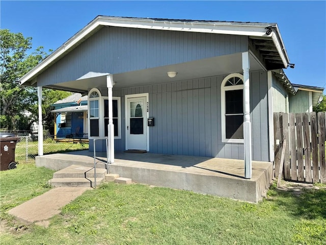 view of front facade featuring a front yard, fence, and covered porch