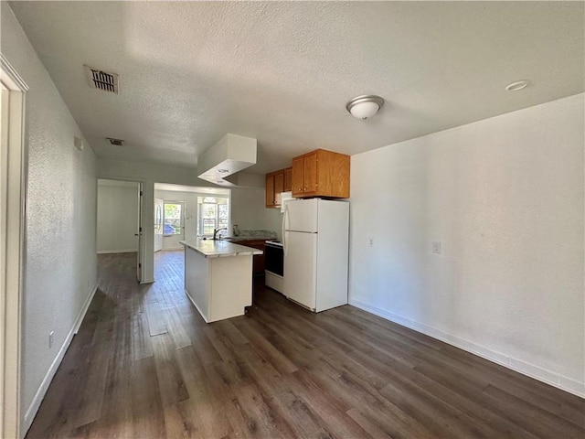 kitchen with white appliances, dark wood-type flooring, a textured ceiling, visible vents, and a kitchen island