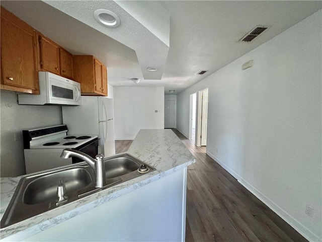 kitchen with white appliances, visible vents, brown cabinets, baseboards, and dark wood-style floors
