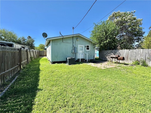 back of house with central AC unit, a fenced backyard, entry steps, and a lawn