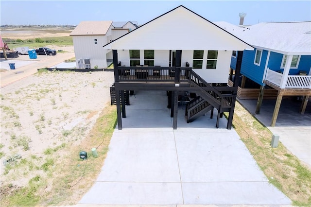raised beach house featuring a carport, stairs, and concrete driveway