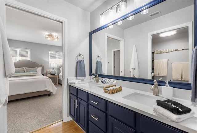 ensuite bathroom with double vanity, visible vents, connected bathroom, and a sink