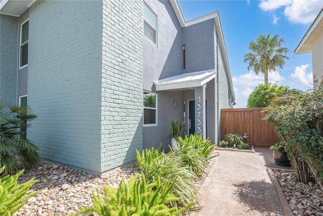 view of home's exterior featuring fence, brick siding, and stucco siding