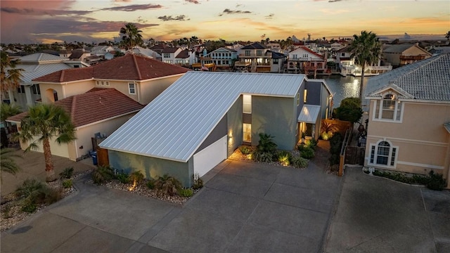 view of front of property with stucco siding, concrete driveway, a garage, a residential view, and metal roof