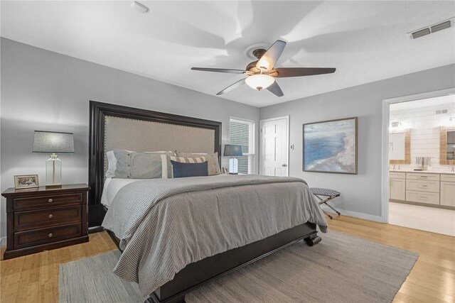 bedroom featuring light wood finished floors, visible vents, connected bathroom, baseboards, and a ceiling fan