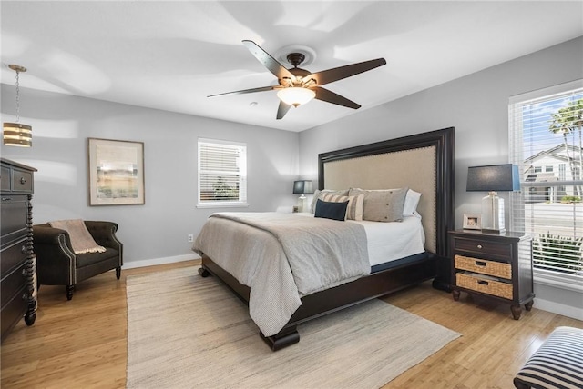 bedroom with a ceiling fan, baseboards, and light wood-type flooring