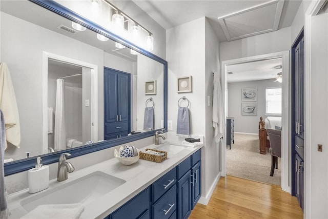 full bath featuring double vanity, wood finished floors, visible vents, and a sink