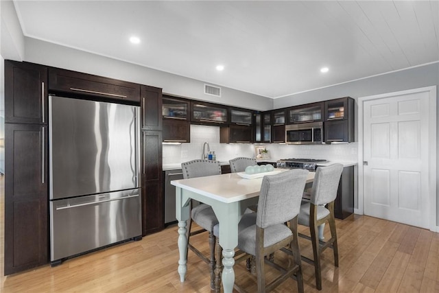 kitchen featuring visible vents, light wood-style flooring, a kitchen breakfast bar, stainless steel appliances, and light countertops