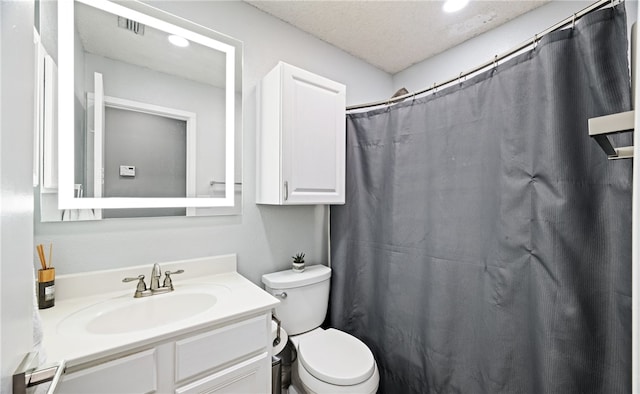 bathroom featuring walk in shower, vanity, toilet, and a textured ceiling