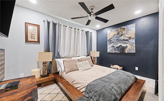 bedroom with ceiling fan, light hardwood / wood-style floors, and a textured ceiling