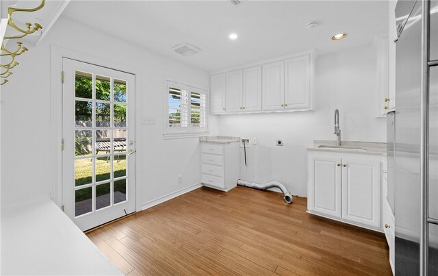 laundry room featuring light hardwood / wood-style floors, electric dryer hookup, cabinets, sink, and hookup for a washing machine