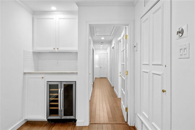 bar with white cabinetry, light hardwood / wood-style floors, backsplash, and wine cooler