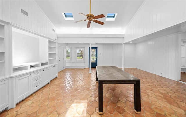 unfurnished living room featuring ceiling fan, wooden walls, and ornamental molding