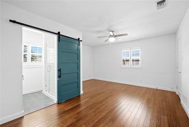 foyer entrance with ceiling fan, a barn door, hardwood / wood-style flooring, and a healthy amount of sunlight