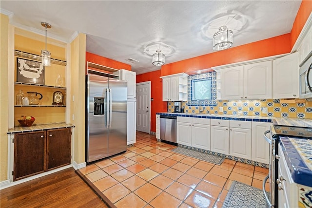 149 Rossiter St, Corpus Christi, TX 78411 - kitchen with stainless steel appliances, tile countertops, white cabinets, and backsplash
