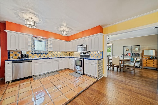149 Rossiter St, Corpus Christi, TX 78411 - kitchen featuring appliances with stainless steel finishes, tile countertops, white cabinets, and ornamental molding