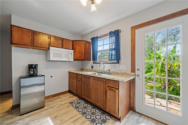 149 Rossiter St, Corpus Christi, TX 78411 - kitchen featuring white microwave, freestanding refrigerator, a sink, and brown cabinetry