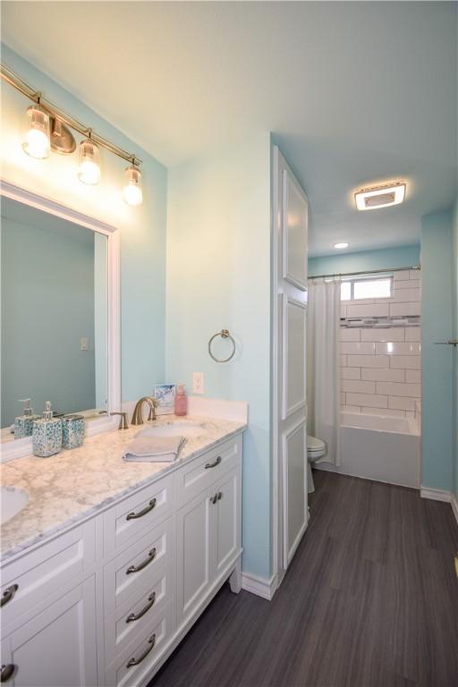 full bathroom with a sink, toilet, wood finished floors, and double vanity