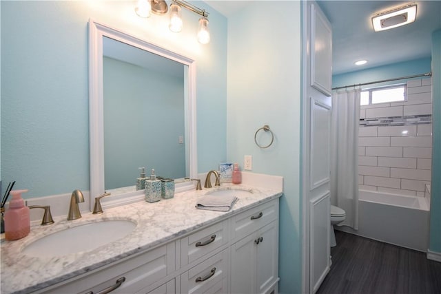 bathroom featuring a sink, toilet, wood finished floors, and double vanity