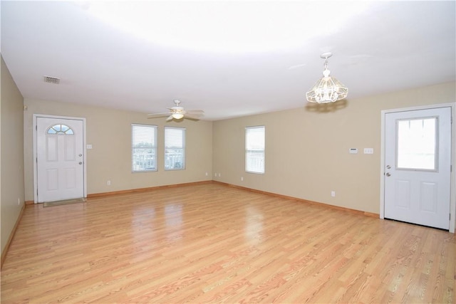 foyer entrance with light wood-type flooring, baseboards, visible vents, and ceiling fan with notable chandelier