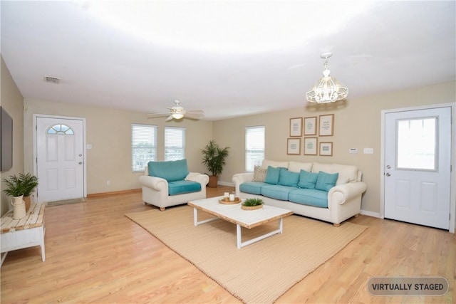 living area with ceiling fan with notable chandelier, wood finished floors, visible vents, and baseboards