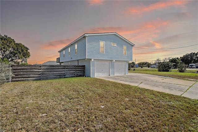 view of side of property with concrete driveway, a garage, fence, and a lawn