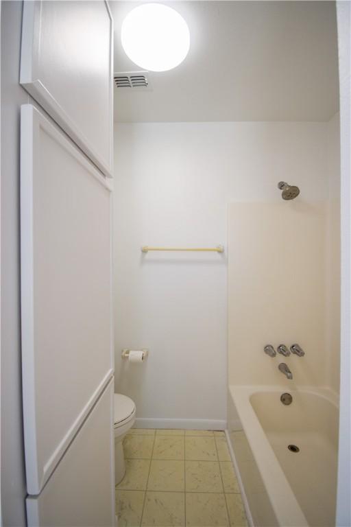 bathroom with visible vents, toilet,  shower combination, and baseboards