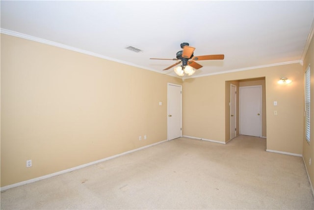 spare room featuring visible vents, baseboards, light colored carpet, ornamental molding, and a ceiling fan