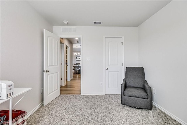 living area with baseboards, visible vents, and light colored carpet