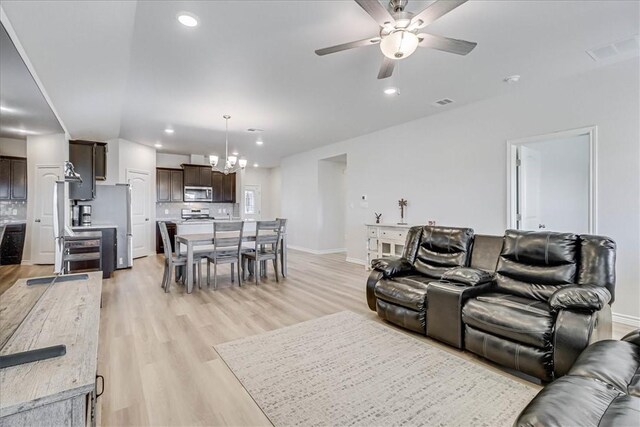 living room with recessed lighting, ceiling fan with notable chandelier, visible vents, baseboards, and light wood finished floors