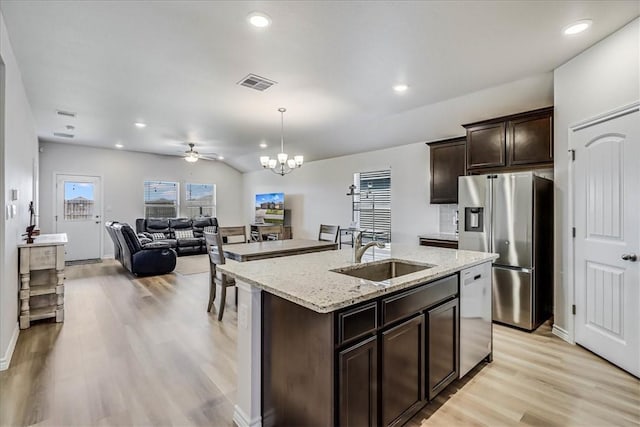 kitchen featuring sink, hanging light fixtures, stainless steel appliances, light hardwood / wood-style floors, and a center island with sink