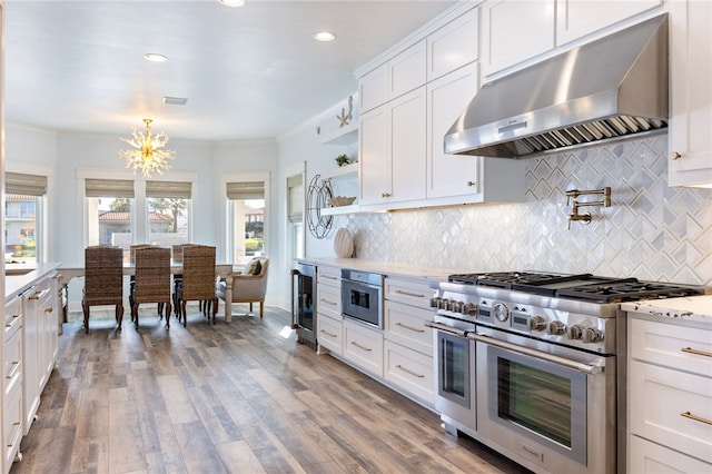 kitchen with range hood, white cabinetry, hardwood / wood-style flooring, and stainless steel appliances