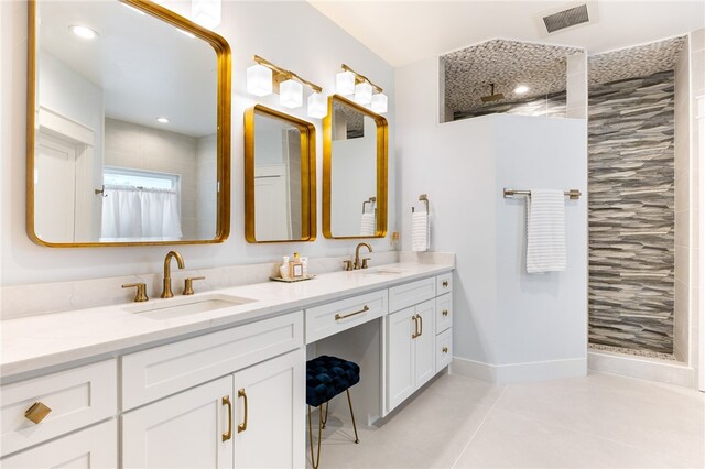 bathroom with tile patterned flooring, tiled shower, and vanity