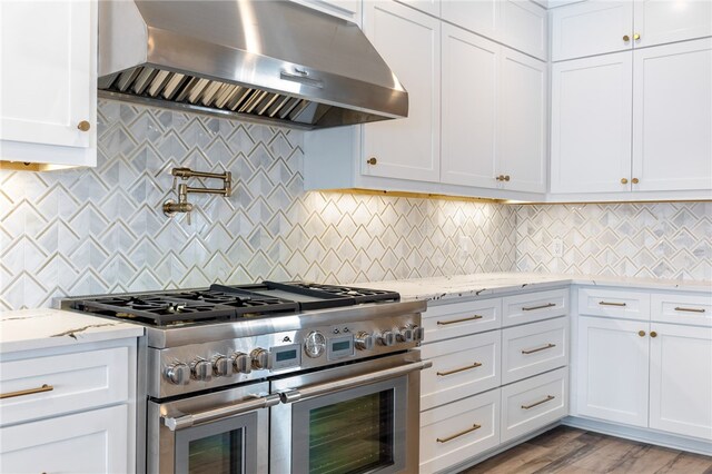 kitchen with white cabinets, wall chimney exhaust hood, double oven range, and backsplash