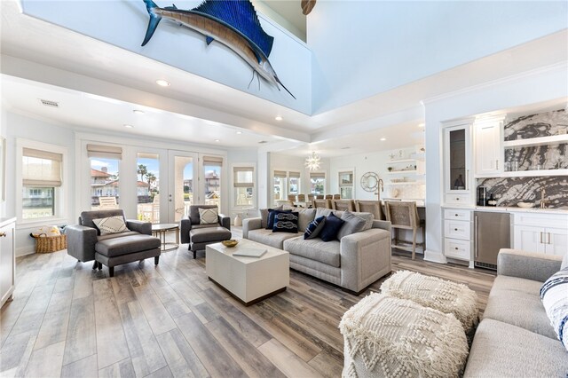 living room featuring hardwood / wood-style floors, a towering ceiling, french doors, and crown molding