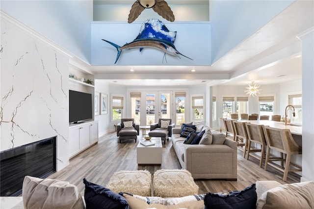 living room with a towering ceiling, an inviting chandelier, and light hardwood / wood-style floors