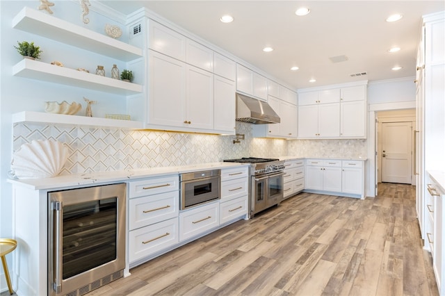 kitchen with stainless steel appliances, beverage cooler, light wood-type flooring, and white cabinets