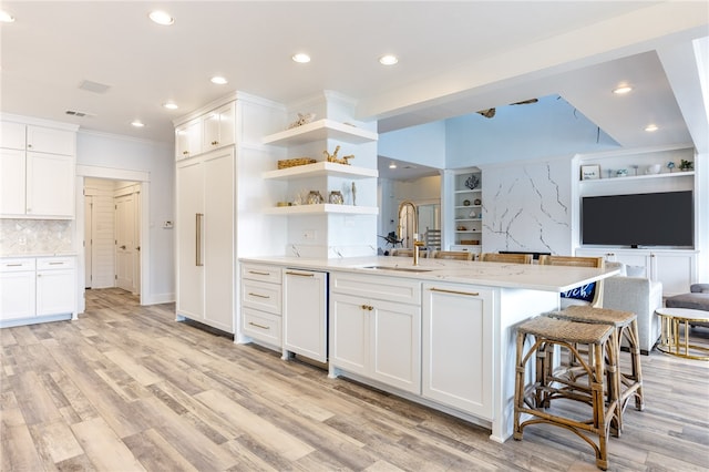 kitchen with white cabinets, light hardwood / wood-style flooring, sink, and backsplash