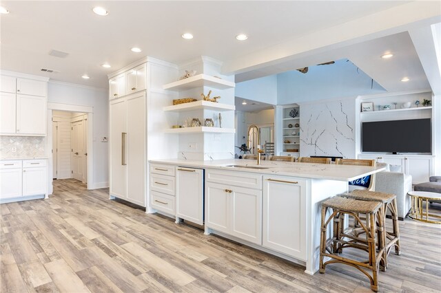 kitchen with white cabinets, light hardwood / wood-style flooring, sink, and backsplash