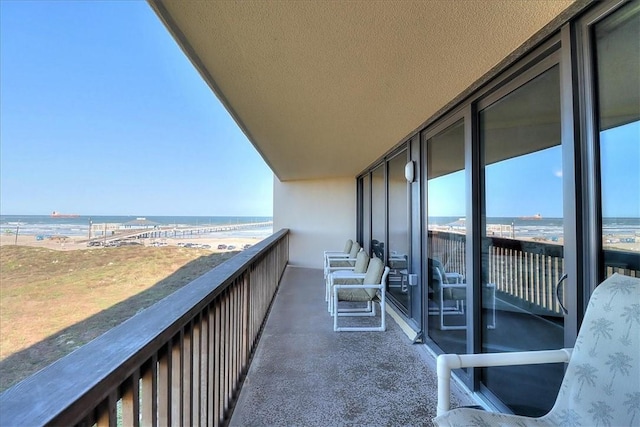 balcony featuring a water view and a view of the beach