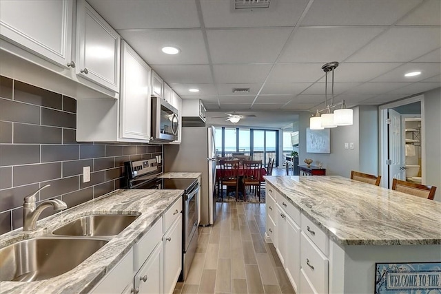 kitchen featuring ceiling fan, white cabinets, decorative light fixtures, and stainless steel appliances