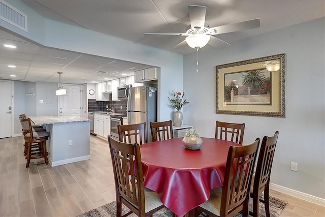 dining space featuring ceiling fan, sink, and light hardwood / wood-style flooring