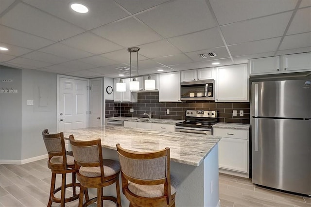 kitchen featuring light stone counters, white cabinets, appliances with stainless steel finishes, and a kitchen island