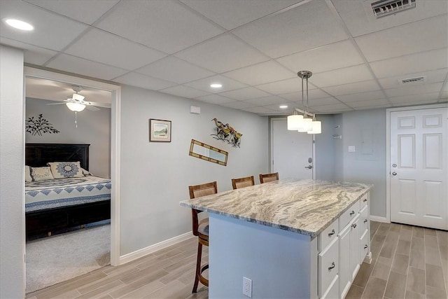 kitchen featuring pendant lighting, white cabinets, a kitchen island, light hardwood / wood-style floors, and a kitchen breakfast bar